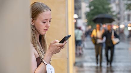 Eine junge Frau schaut am 30. Juli 2022 in München in ihr Smartphone.
