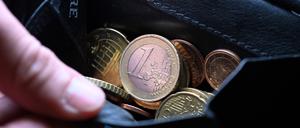 Eine Hand greift in einen Geldbeutel mit Münzen