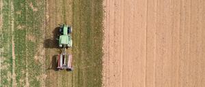 Ein Landwirt fährt mit einem Traktor neben einem abgeernteten Feld entlang. (Symbolbild)