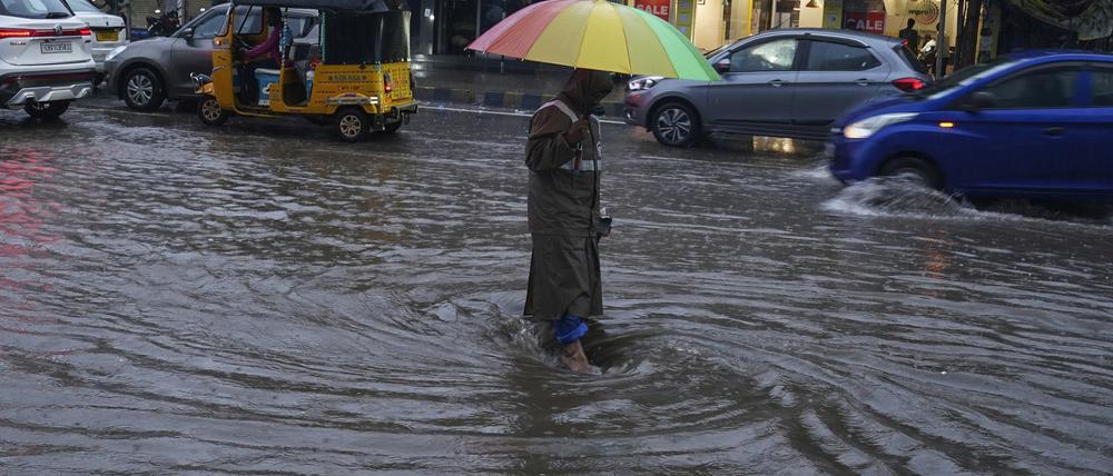 20.07.2023, Indien, Hyderabad: Ein Mann geht durch eine überflutete Straße. In Indien fällt der Monsunregen von Juni bis Oktober. Starke Regenfälle, die heftige Überflutungen und Erdrutsche auslösen, sind in der Monsunzeit in Südasien normal. Der Monsun dauert gewöhnlich von Juni bis September. Foto: Mahesh Kumar A./AP/dpa +++ dpa-Bildfunk +++