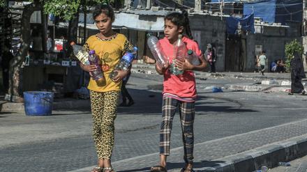 Palästinensische Mädchen tragen Wasserflaschen.