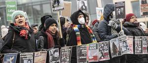 Teilnehmer an einer Protestaktion gegen das Iran-Regime stehen mit Plakaten auf dem Pariser Platz. 