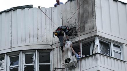 Ein Spezialist inspiziert die beschädigte Fassade eines mehrstöckigen Wohnhauses nach einem Drohnenangriff in Moskau: