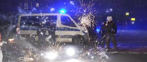 Polizeibeamte stehen am 31.12.2022 hinter explodierendem Feuerwerk.