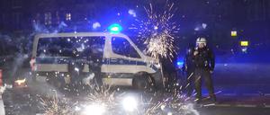Polizeibeamte stehen am Silvesterabend hinter explodierendem Feuerwerk. 