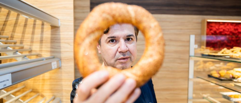 Bäckereiinhaber Mehmet Cevik hält in seiner türkischen Cevik-Bäckerei in Berlin-Wedding einen Simit in die Kamera.