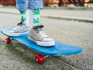 Junge Frau mit Marihuana-Socken auf einem Skateboard.