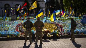 Ukrainische Soldaten stehen auf dem Unabhängigkeitsplatz im Zentrum von Kiew neben ukrainischen Flaggen und Fotos, die zum Gedenken an im Krieg gefallene Zivilisten und Soldaten aufgestellt wurden. 