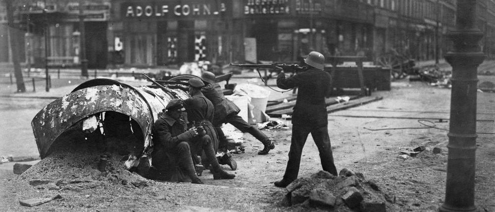 Hinter einer umgestürzten Litfaßsäule in Berlin gehen im März 1919 Soldaten der Regierungstruppen in Stellung.