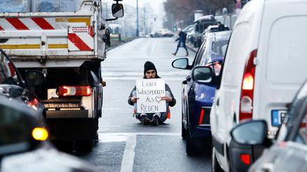 Ein Aktivist zeigt ein Schild mit der Aufschrift „Lieber Wegsperren als Reden“ bei einer Sitzblockade mit weiteren Aktivisten auf der Prenzlauer Allee.