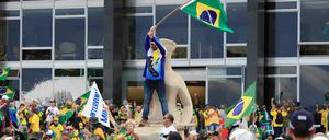 Anhänger des ehemaligen brasilianischen Präsidenten Bolsonaro stehen auf dem Dach des Kongressgebäudes in Brasilia. 