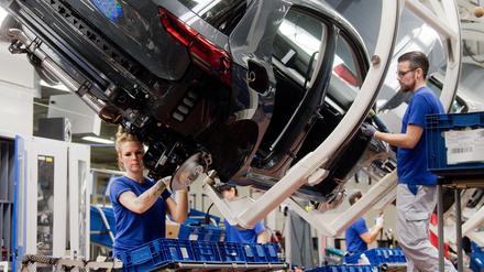 Mitarbeiter arbeiten an einem Volkswagen Golf 8 an einer Produktionslinie im VW Werk. 