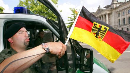 Polizeiobermeister Marco Däfler befestigte bei der Fußball-Weltmeisterschaft 2006 vor dem Berliner Reichstag eine Deutschlandfahne an seinem Polizeiwagen.