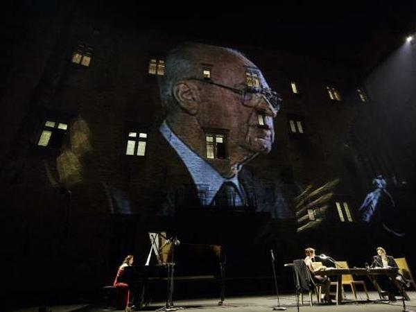 Unten auf der Bühne Schauspiel, oben die Dokumentarbilder. Bild aus Amos Gitaïs "Yitzhak Rabin : chronique d'un assassinat".