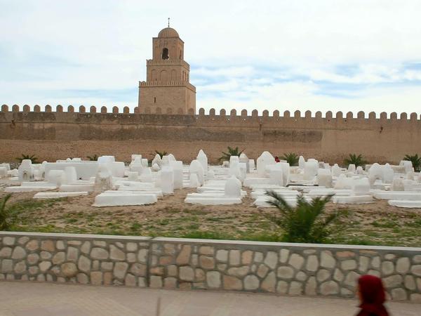 Friedhof vor den Toren der Stadt. Das Minarett der Sidi Okba Moschee, der viertwichtigsten Moschee des Islam, wurde nach dem Vorbild eines römischen Leuchtturms errichtet.