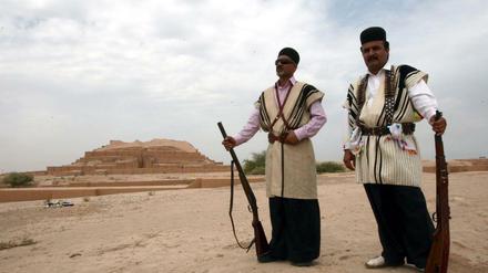 Zwei iranische Männer stehen in traditioneller Kleidung vor einem Ziggurat nahe Susa, das ab heute den Titel Weltkulturerbe trägt. 