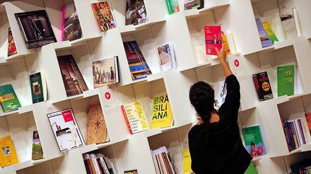 Eine Frau sortiert auf der Buchmesse in Frankfurt am Main Bücher im Pavillon des Gastlandes Brasilien. Die weltweit größte Messe ihrer Art dauert noch bis 13. Oktober.