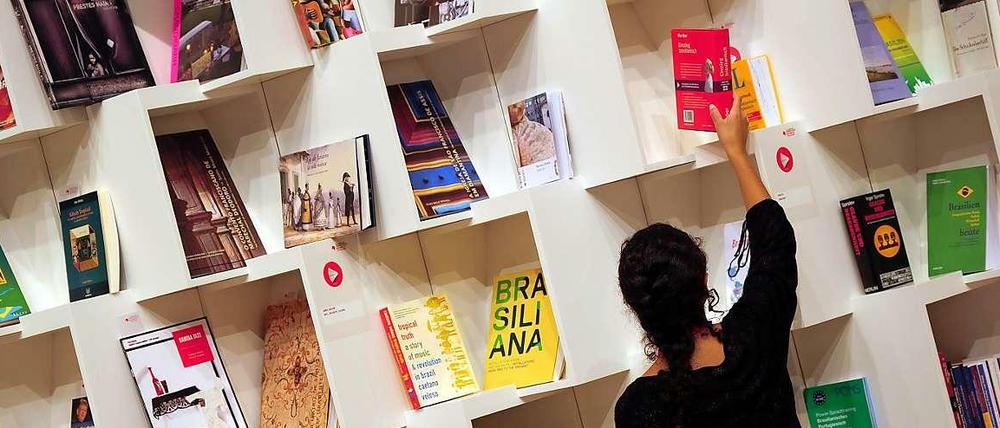 Eine Frau sortiert auf der Buchmesse in Frankfurt am Main Bücher im Pavillon des Gastlandes Brasilien. Die weltweit größte Messe ihrer Art dauert noch bis 13. Oktober.