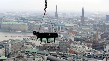 Ein Flügel hängt an einer Vorrichtung über den Dächern von Hamburg.