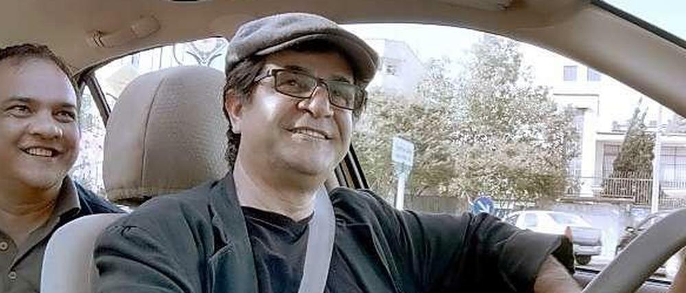 Er kann immer noch lächeln: Jafar Panahi (r.) hat bereits viele Rückschläge erlebt. Doch er übt seinen Beruf unverdrossen weiter aus - wie hier in seinem Gewinnerfilm "Taxi".