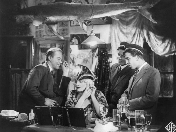 Szenenfoto aus "Der blaue Engel". In der Mitte Marlene Dietrich als Lola.