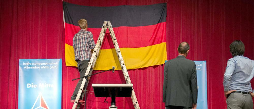 Helfer hängen vor der 1. Deutschlandtagung der Alternativen Mitte der AfD in Tettau (Bayern) eine Deutschlandfahne auf.