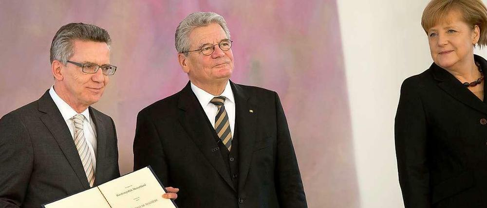 Bundespräsident Joachim Gauck überreicht am Dienstag im Schloss Bellevue in Berlin die Ernennungsurkunde an den neuen Bundesinnenminister, Thomas de Maizière (l, CDU). Rechts steht Kanzlerin Angela Merkel (CDU).