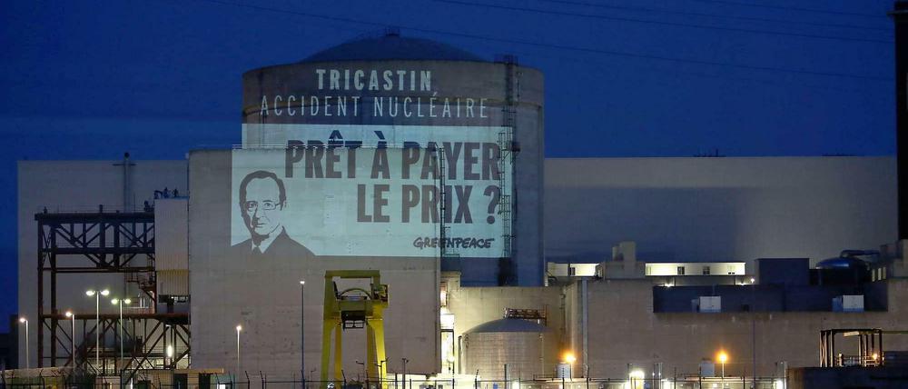 Eine Protestaktion von Greenpeace projiziert ein Bild des französischen Präsidenten und die Frage "Bereit, den Preis zu zahlen?" an die Wand des Atomkraftwerks Tricastin.