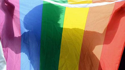 Ein Mann hält eine Regenbogenfahne als Symbol der Schwulen- und Lesbenbewegung.