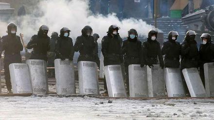 Polizisten stehen aufgereiht und beobachten die Demonstranten in Kiew. 