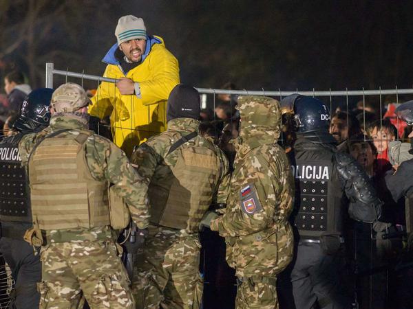 Slowenische Polizisten halten Flüchtlinge zurück, die die Grenze Richtung Österreich überqueren wollen.