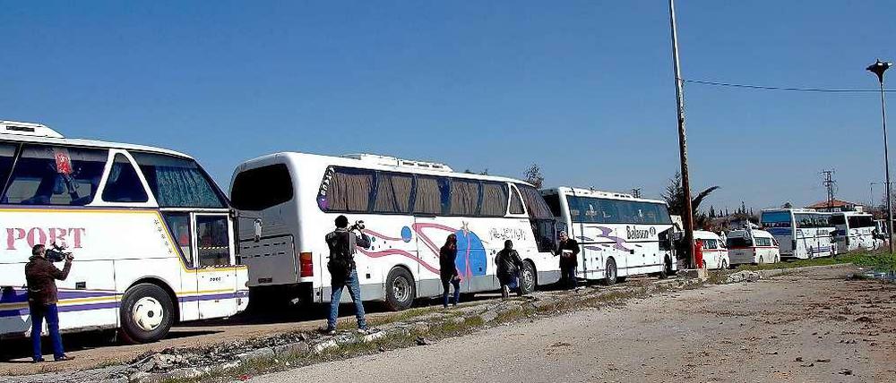 Die ersten Bewohner der syrischen Stadt Homs verlassen in Bussen und Krankenwagen ihre Heimat.