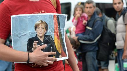 Ein Flüchtling hält am Bahnhof München ein Bild von Angela Merkel in der Hand.
