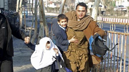 Ein Mann bringt nach einer Explosion vor dem pakistanischen Konsulat in Dschalalabad seine Familie in Sicherheit. 