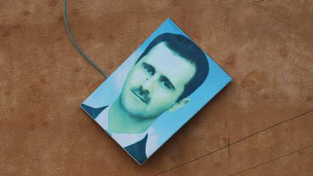Das Bild von Syrischen Präsident Bashar al-Assad wird von einer Wand in Ariha gestoßen. 