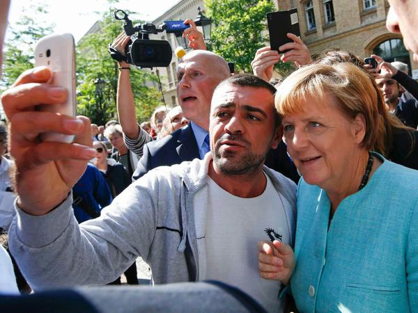 Selfie mit der Kanzlerin: Beim Besuch der Außenstelle des Bundesamts für Migration in Spandau bittet ein Syrer Angela Merkel um ein Foto.
