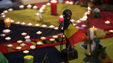Eine Miniaturskulptur von Manneken Pis hält die belgische Flagge. Am Place de la Bourse (Beursplein) in Brüssel trauern  die Menschen.