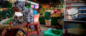 Masken in Mali. Eine Gemüseverkäuferin auf dem zentralen Markt von Bamako versucht, sich gegen das Coronavirus zu schützen.
