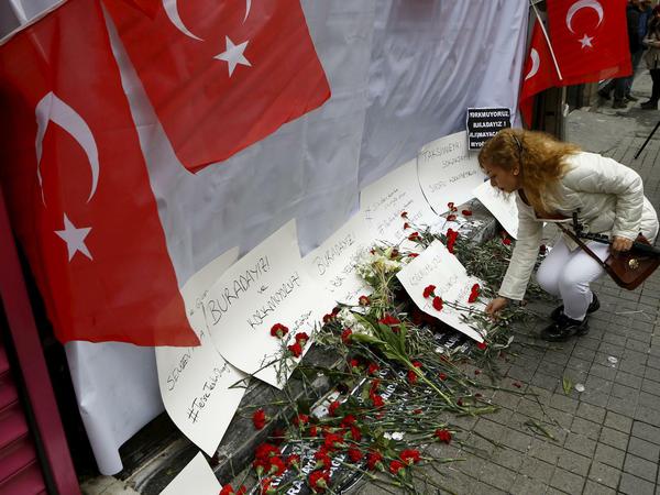 Eine Frau legt am Anschlagsort in der Istiklal-Straße in Istanbul Blumen nieder.