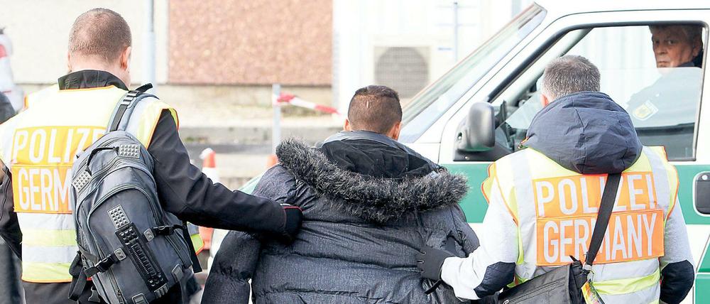 Polizisten begleiten einen straffällig gewordenen Asylbewerber am 24.11.2015 zum Flughafen Leipzig-Halle in Schkeuditz (Sachsen) zu seinem Abflug nach Belgrad (Serbien). Foto: Sebastian Willnow/dpa +++(c) dpa - Bildfunk+++
