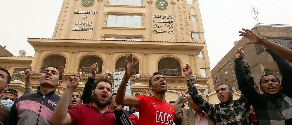 Anhänger der Muslimbrüderschaft bei einer Demonstration vor dem Hauptsitz der Bewegung in Kairo (im Hintergrund). Ab sofort sind sie in Ägypten verboten.