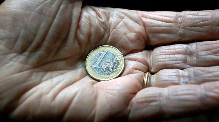 In der Hand eines alten Menschen liegt eine Euro-Münze