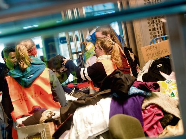 Improvisationstalente: Helfer am Münchener Hauptbahnhof in München versorgen eine Familie aus Syrien mit den nötigsten Lebensmitteln und Kleidungsstücken. 