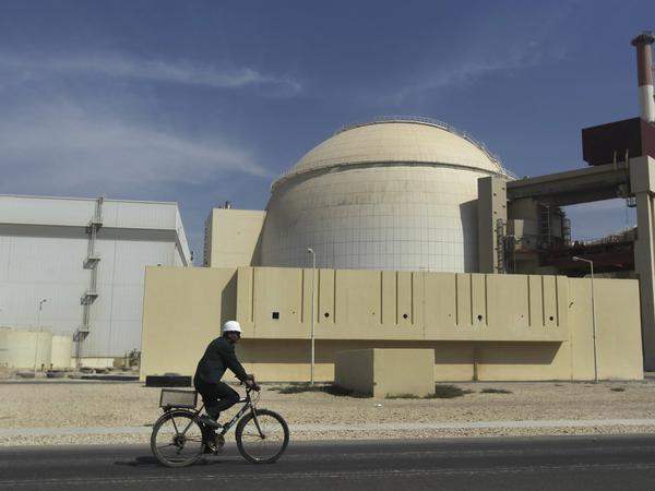 Ein Arbeiter fährt mit seinem Fahrrad vor dem Reaktorgebäude am Atomkraftwerk Buschehr in Iran.