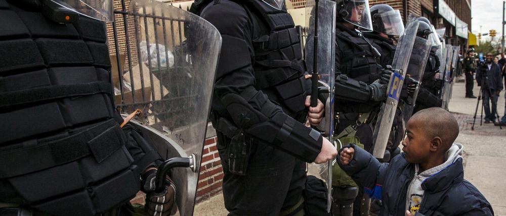 Ein Junge begrüßt Polizisten in Baltimore. Der soziale Frieden ist in der Ostküstenstadt vorläufig wieder hergestellt.