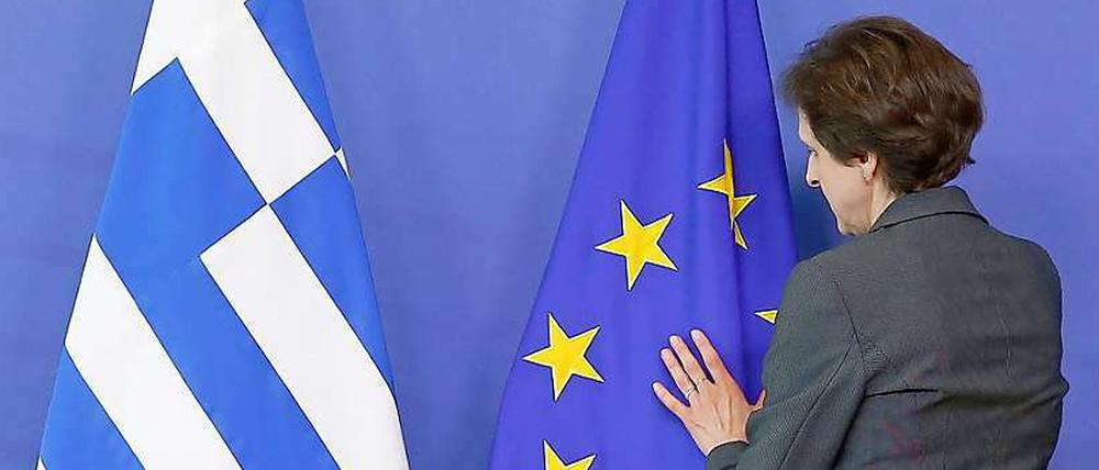 Exakter Faltenwurf. Eine Mitarbeiterin des Protokolls drapiert in Brüssel die Flaggen Griechenlands und der EU. 