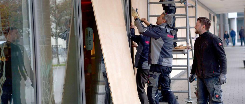 Arbeiter sichern am Freitag die Fensterscheiben an einem Hotel am Zentralen Omnibusbahnhof (ZOB) in Hannover mit Holzplatten.