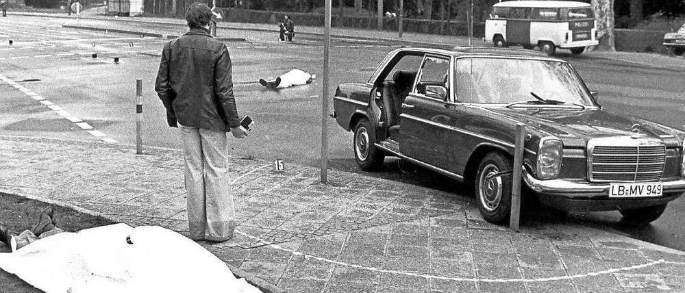 Der Tatort mit den zugedeckten Leichen von Siegfried Buback (vorne links) und seines Fahrers sowie der Dienstwagen des Generalbundesanwaltes, aufgenommen am 07.04.1977.