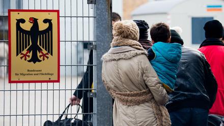 Flüchtlinge stehen 2015 neben einem Schild vom "Bundesamt für Migration und Flüchtlinge" an der Landesaufnahmebehörde Niedersachsen in Braunschweig.