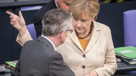Bundesinnenminister Thomas de Maiziere (CDU) spricht mit Bundeskanzlerin Angela Merkel (CDU) am 01.10.2015 im Bundestag in Berlin. 